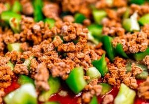 Macro closeup of homemade uncooked pizza with tomato sauce and toppings green bell peppers chopped with ground vegan beef crumbles Macro closeup of homemade uncooked pizza with tomato sauce and toppings green bell peppers chopped with ground vegan beef crumbles